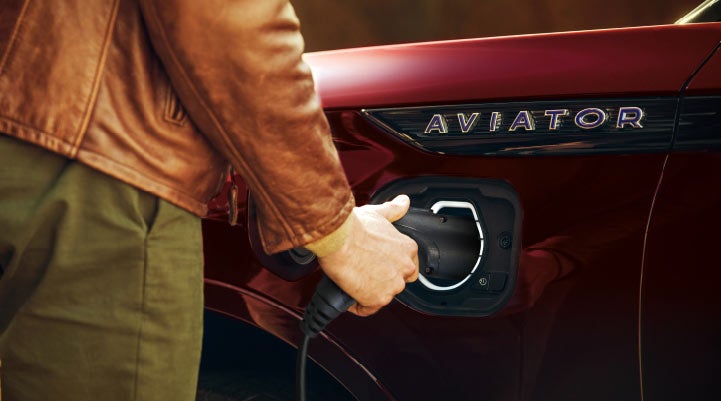 A hand is shown plugging in the charger into the charging port of a 2021 Lincoln Aviator | Golden Circle Lincoln in Jackson TN